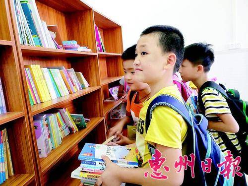 山下小学学生在读书屋里开心地看课外读物。