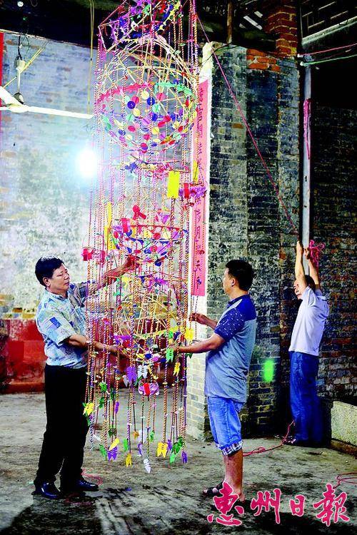  生前的何富声（左）与工作人员一同悬挂永汉非物质文化遗产——— 虎头花灯。
