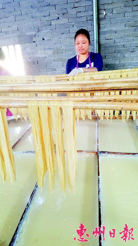 黄玉娴将腐竹挑起来，放到竹竿上。