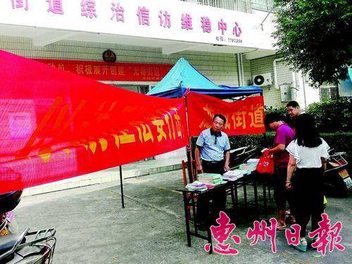  黄球根（左一）向群众发法律宣传资料。 